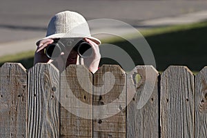 Spying over fence with binoculars