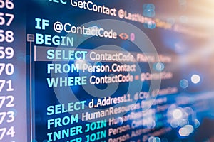 SQL (Structured Query Language) code on computer monitor and server room background.