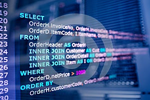 SQL (Structured Query Language) code on computer monitor and server room background.