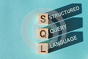 SQL text on wooden blocks, financial business concept, blue background. SQL - short for Structured Query Language