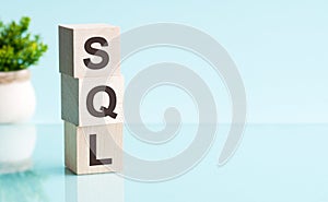 SQL word in wooden blocks on table. blue background, copy space