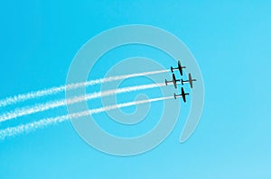 Squad of four airplanes flying together leaving a smoke trail be