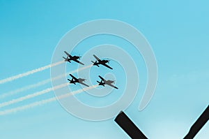 Squad of four military airplanes flying together leaving a smoke