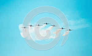 Squad of seven airplanes flying together on line leaving a smoke