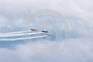 Squadron of planes fly with color trail in white lines over clouds and clear sky, fly inspirations, Banesti, Romania