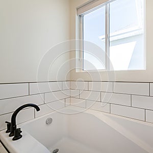 Square Alcove bathtub with white subway tiles surround with black grout