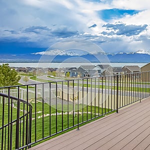 Square Balcony with wooden floor and metal railing overlooking lake and mountain