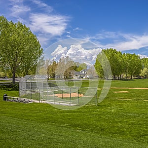 Square Baseball or softball field against lush trees and buildings under cloudy sky