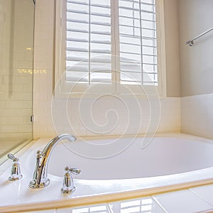 Square Bathroom interior with built in bathtub and shiny towel rod on the white wall