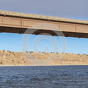 Square Beam bridge with abutment foundation against rugged land and cloudy sky