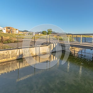 Square Bridge over lake with lakefront buildings and mountain view under blue sky