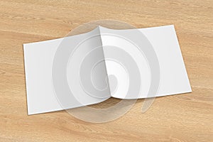 Square brochure or booklet cover mock up on wooden background. Brochure is open and upside down. Isolated with clipping path aroun