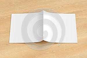 Square brochure or booklet cover mock up on wooden background. Brochure is open and upside down. Isolated with clipping path aroun