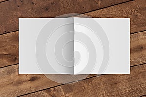 Square brochure or booklet cover mock up on wooden background. Brochure is open and upside down. Isolated with clipping path aroun