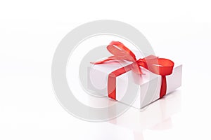 Square cardboard gift box tied with red satin ribbon and bow isolated on white