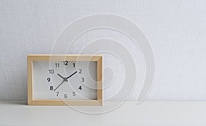 A square clock in front of a white wall