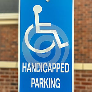 Square Close up of Handicapped Parking sign against blurred red brick wall of church