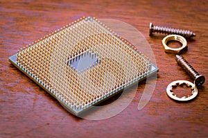 A square computer processor pulled from a broken computer. The processor is on the table.