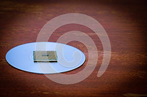 A square computer processor pulled from a broken computer. The processor is on the table.