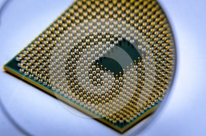 A square computer processor pulled from a broken computer. The processor is on the table. View of the contacts through a magnifyin
