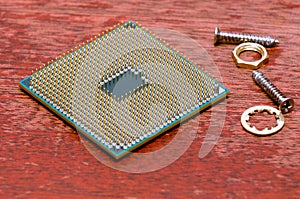 A square computer processor pulled from a broken computer. The processor is on the table. View on the contacts.