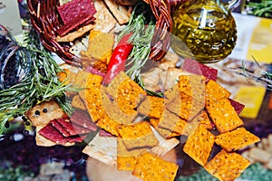 Square cracker scattered on the table and decorated with herbs. Still life of pryango cookies with hot peppers. Close-up.