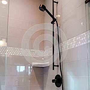 Square crop Black round shower head on tile wall of shower stall with hinged glass door