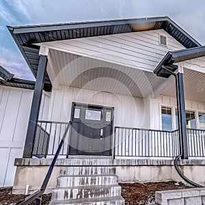 Square crop Home exterior with snow dusted yard against bright blue sky and clouds in winter