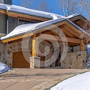 Square crop Home in Park City Utah with snowy gable roofs stone wall and outdoor stairs