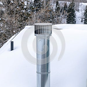 Square crop Shiny metal chimney vent pipe on the roof of home covered with snow in winter