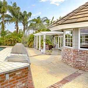 Square Day shot of a wonder California home with a large pool and counter space for a barbeque on a bright sunny day