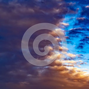 Square Defocussed view of a vast blue sky filled with puffy dark clouds at sunset