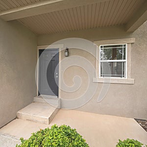 Square Entrance of a house with black front door and concrete doorsteps