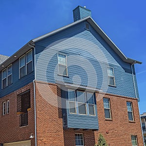 Square Exterior of homes with wooden and red brick wall against blue sky on sunny day