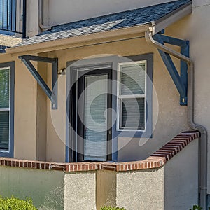 Square Facade of home with pathway that leads to the porch and glass paned front door