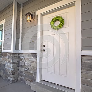 Square Facade of a home with a simple wreath hanging on the white wooden door