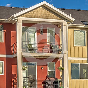 Square Facade of townhouse with gable roof over balconies against blue sky background