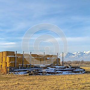 Square Farm in Eagle Mountain Utah with stacks of hay and snowy logs in winter