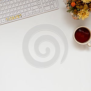 Square Flat Lay of an office: laptop keyboard, coffee and plants. With copy space white background