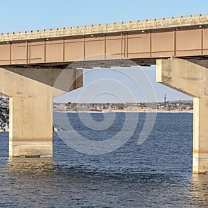 Square Focus on a beam bridge supported by abutments over blue lake against cloudy sky