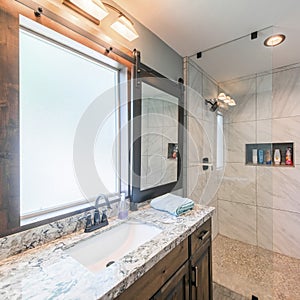 Square frame Bathroom interior with tile walls, warm lightnings and sliding window panel with mirror