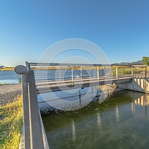 Square frame Bridge over lake with lakefront buildings and mountain view under blue sky