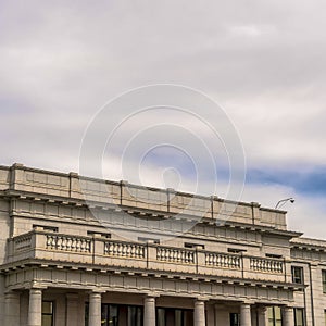 Square frame Building with white wall balcony and security camera on roof against cloudy sky