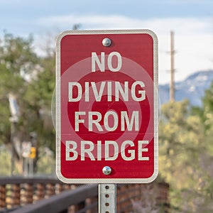 Square frame Close up of a No Diving sign beside a bridge with brown metal guardrail
