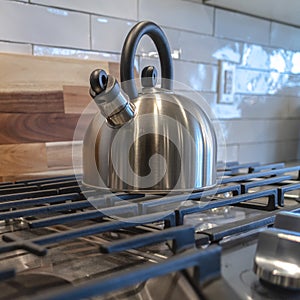 Square frame Cookpot with kettle against wooden chopping board and tile backsplash