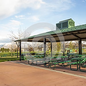 Square frame Covered picnic area on a scenic park under cloudy blue sky