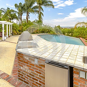 Square frame Day shot of a wonder California home with a large pool and counter space for a barbeque on a bright sunny