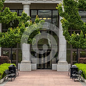 Square frame Entrance to a white building with pavement leading to the glass door entryway