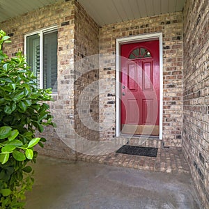 Square frame Exterior of an entrance of house with red door, windows, plants and bricks