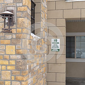 Square frame Exterior view of apartments with No Smoking sign on the stone brick wall